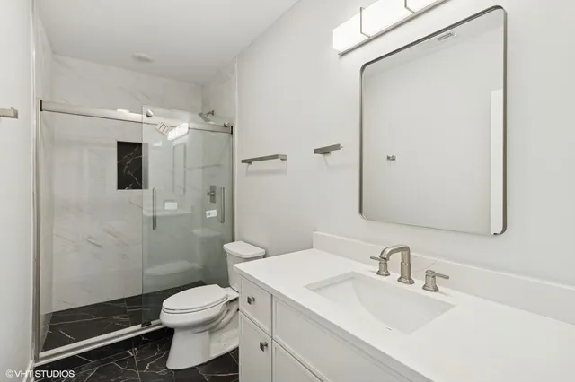 a bathroom with a sink toilet vanity and shower