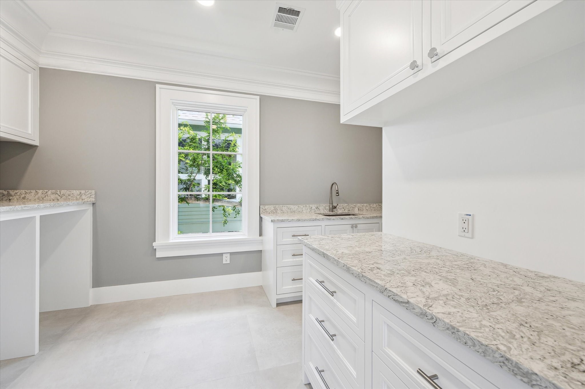 2216 Tangley Street Houston, TX 77005 - Photo 17 of 44 This second floor room features a bright and spacious laundry and utility area with ample white cabinetry, hard-surface countertops, and a large window providing natural light.