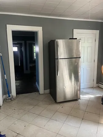 a view of a refrigerator in kitchen and an empty room