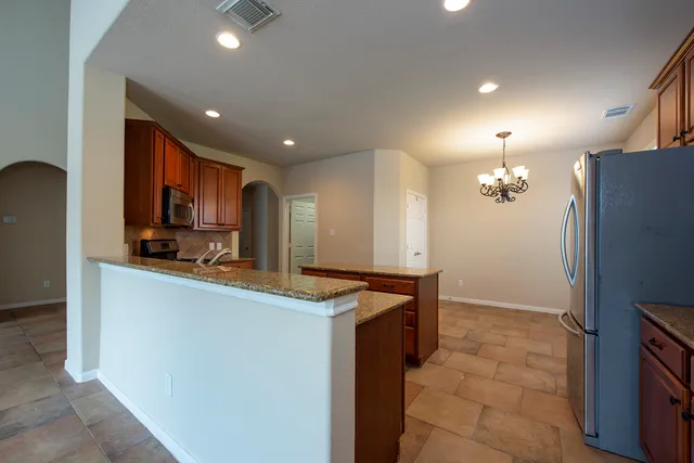 a kitchen with stainless steel appliances granite countertop a refrigerator a sink dishwasher and a stove with wooden floor