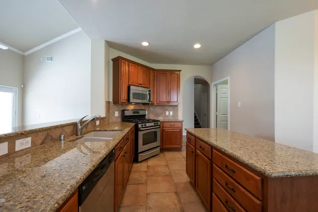 a large kitchen with granite countertop a sink and a stove