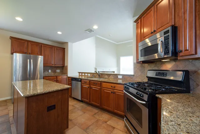 a kitchen with stainless steel appliances granite countertop a stove a sink and a microwave