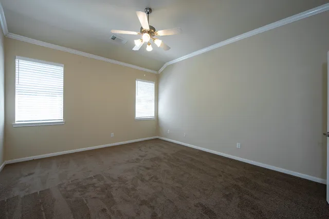 an empty room with windows and chandelier fan
