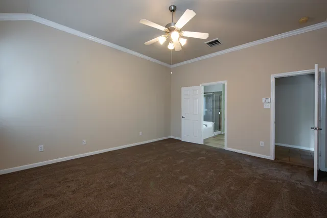 an empty room with a chandelier fan and windows