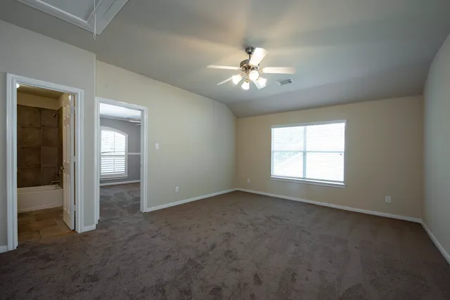 an empty room with chandelier fan and windows