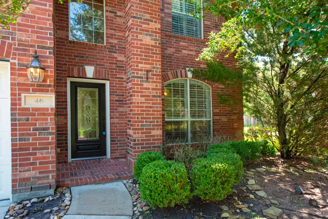 a view of a brick house with a large window and a potted plant