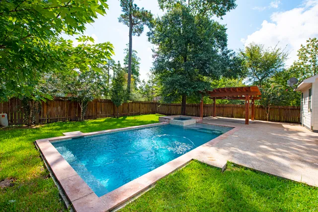 a view of a park with large trees and a wooden fence