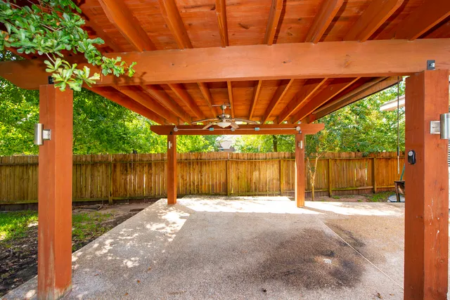 a view of a backyard with wooden fence and a large tree