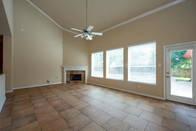 an empty room with windows chandelier fan and windows