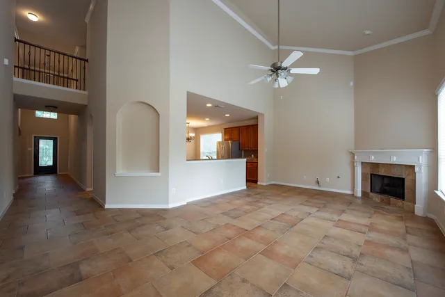 an empty room with fan and view of a kitchen