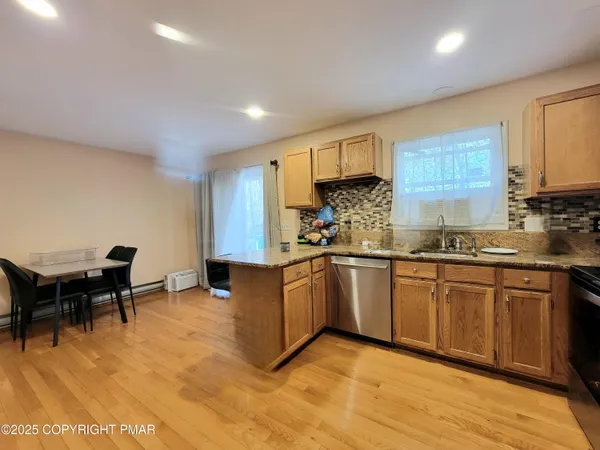 a kitchen with granite countertop a stove a sink a dining table and chairs