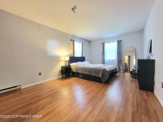 a spacious bedroom with a bed and wooden floor