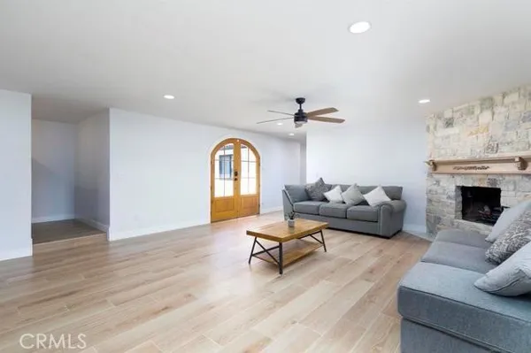 a living room with stainless steel appliances kitchen island granite countertop a refrigerator a sink dishwasher a oven with white cabinets and wooden floor