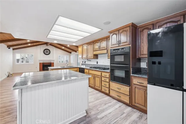 a kitchen with stainless steel appliances granite countertop a refrigerator a stove and a sink with wooden floor