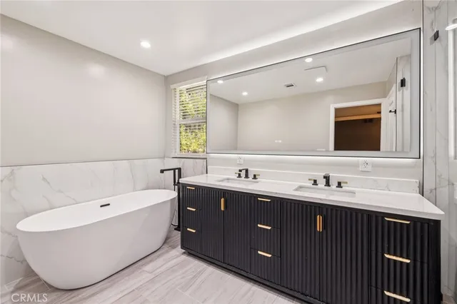 a bathroom with a tub sink double vanity and mirror