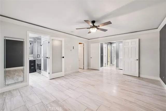 a view of an empty room with wooden floor and a ceiling fan