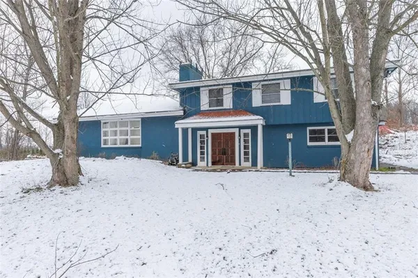 a front view of a house with a yard covered in snow