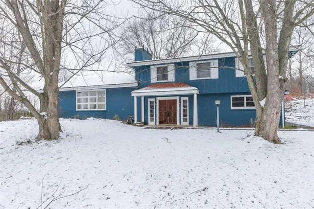 a front view of a house with a yard covered in snow