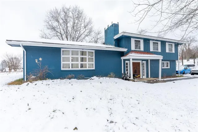 a front view of a house with a yard covered in snow