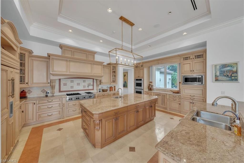 2116 Canna Way Naples, FL 34105 - Photo 31 of 50 a large kitchen with stainless steel appliances a stove a sink a oven a dining table and chairs with wooden floor