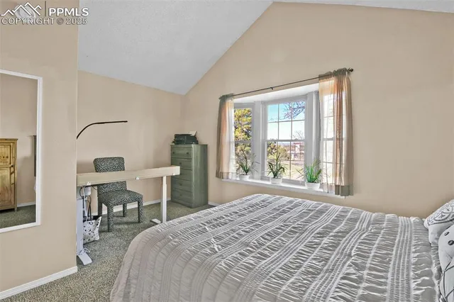 a bedroom with a bed a table and a large mirror next to a window