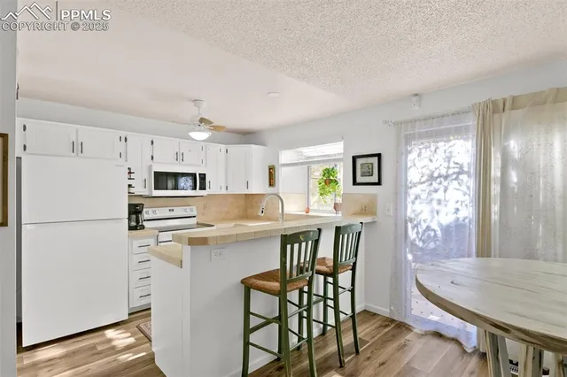 a kitchen with stainless steel appliances a white table chairs and a refrigerator
