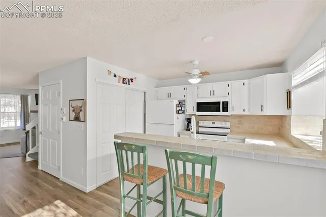 a kitchen with kitchen island granite countertop a table chairs microwave and cabinets