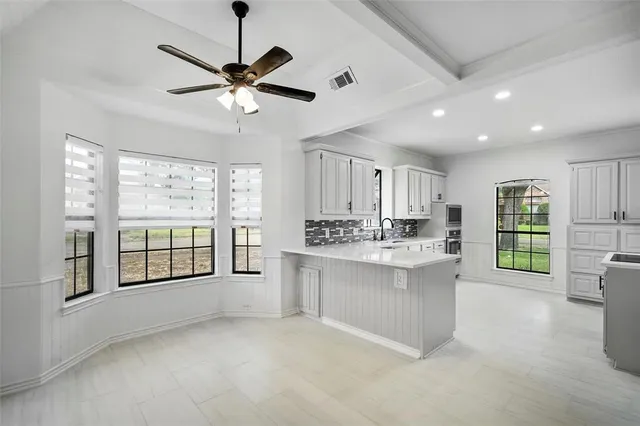 a kitchen with white cabinets and window