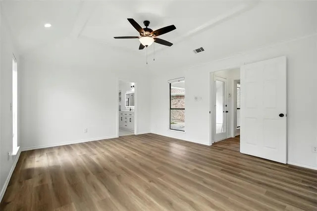a view of empty room with wooden floor and fan