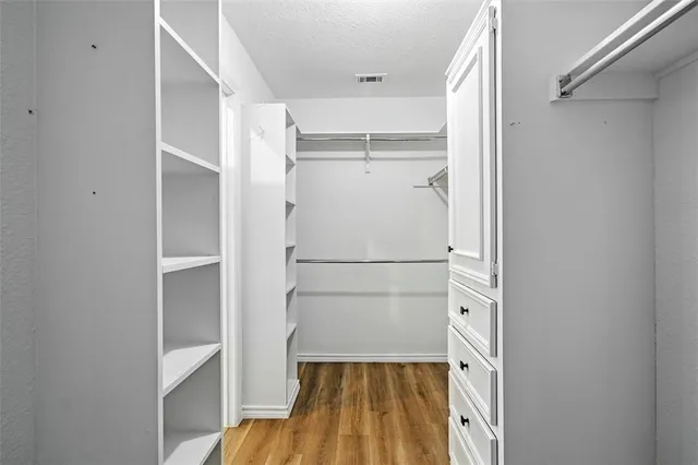 a view of empty room with wooden floor and fan