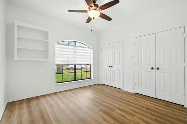 an empty room with wooden floor closet and windows