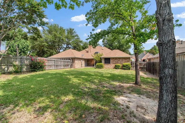 a small house with a wooden fence and trees