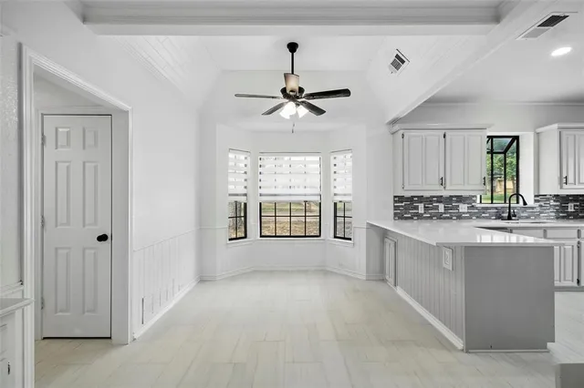 a large white kitchen with a large window appliances and cabinets