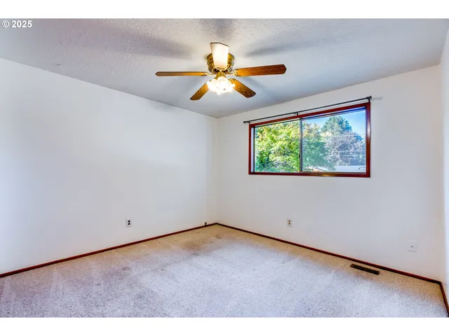 an empty room with window and ceiling fan
