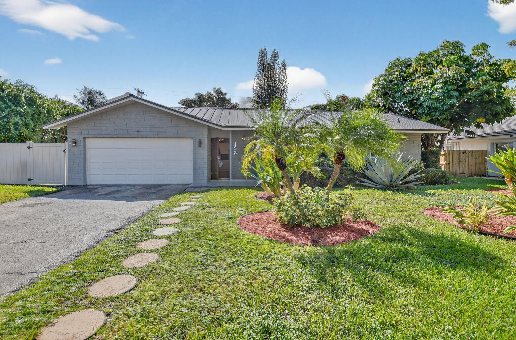 1650 Northwest 9th Street Boca Raton, FL 33486 - Photo 46 of 57 a front view of a house with a yard and garage