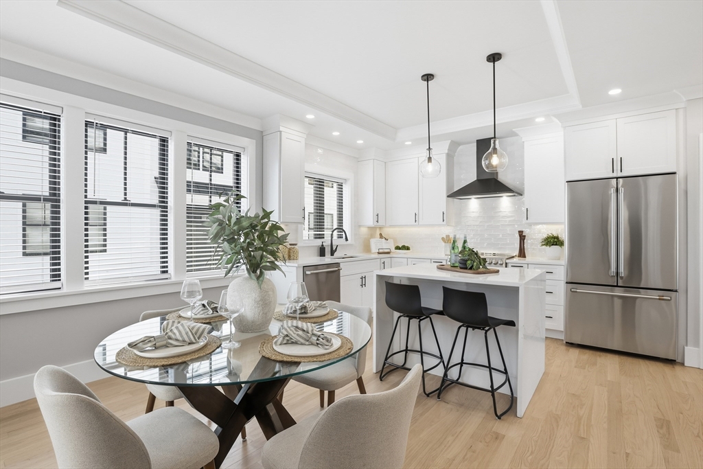 10 Webber Avenue, Unit 101 Bedford, MA 01730 - Photo 10 of 35 a kitchen with stainless steel appliances granite countertop a dining table chairs and white cabinets