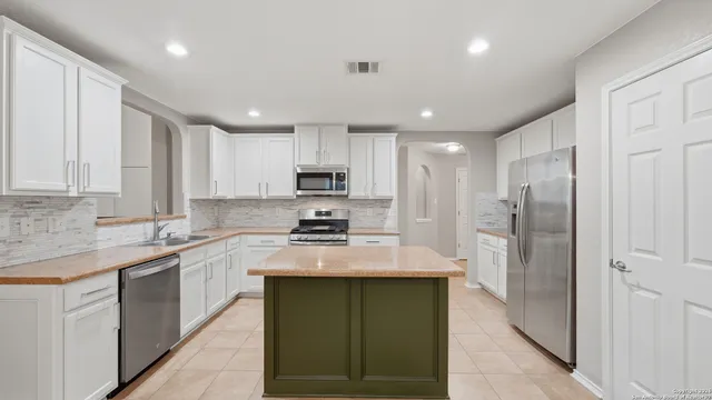a kitchen with stainless steel appliances granite countertop a sink a stove a refrigerator a center island and cabinets