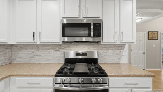 a kitchen with stainless steel appliances granite countertop white cabinets and black stove top oven with granite countertops