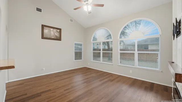 a view of empty room with wooden floor and fan