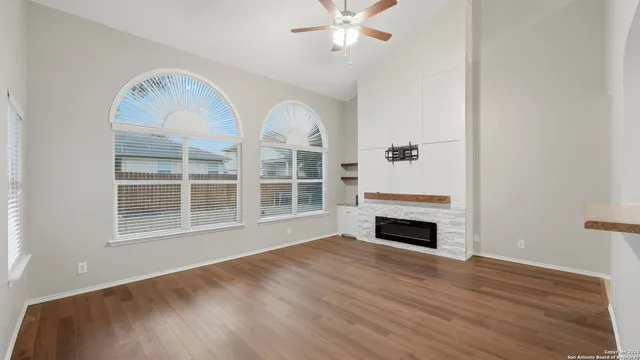a view of an empty room with wooden floor fireplace and a window