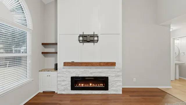 a view of an empty room with wooden floor and a fireplace