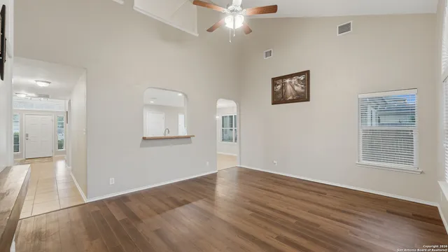 a view of an empty room with wooden floor and a window