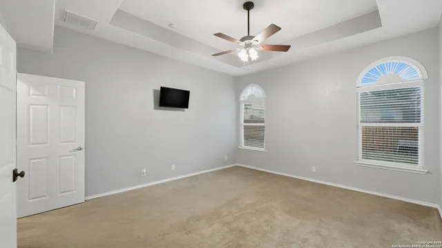 en empty room with windows and chandelier fan