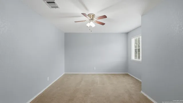 an empty room with a window and a fan
