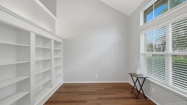 a view of an empty room with a window and wooden floor