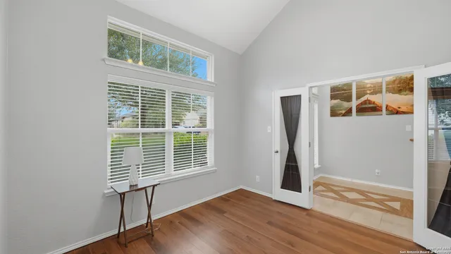 a view of an empty room with a window and wooden floor