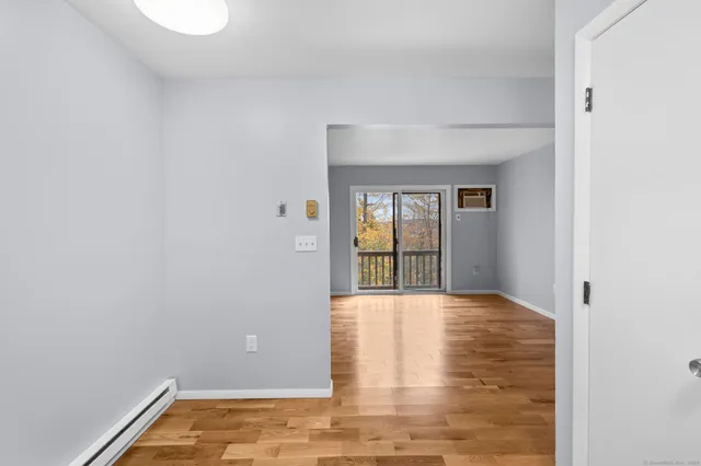 a view of an empty room with wooden floor and a window