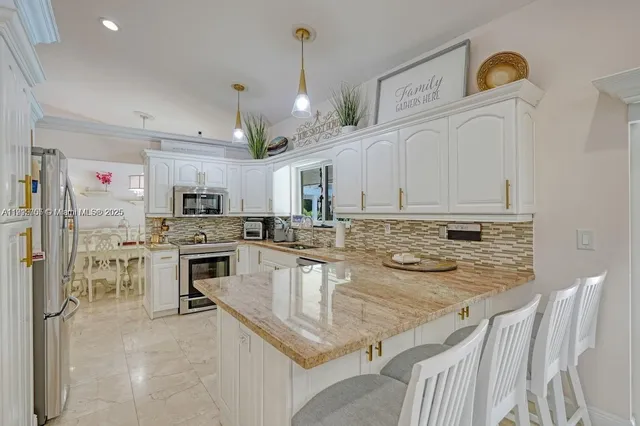 a kitchen with stainless steel appliances granite countertop a sink a stove and cabinets