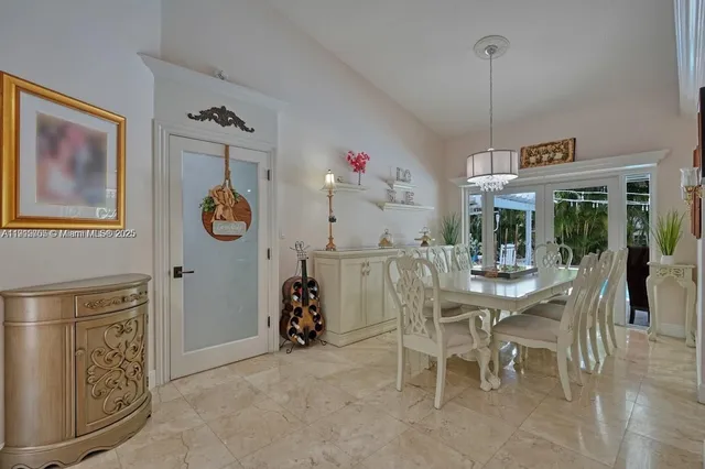 a view of a dining room and livingroom with furniture wooden floor a rug a painting and a chandelier