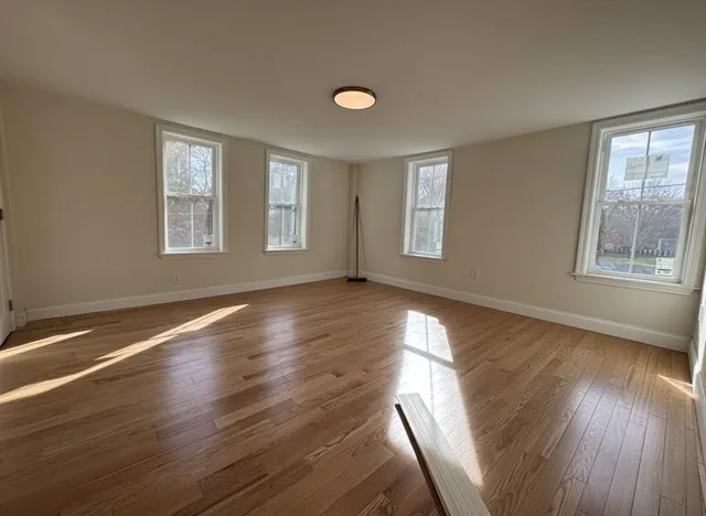 a view of an empty room with wooden floor and a window